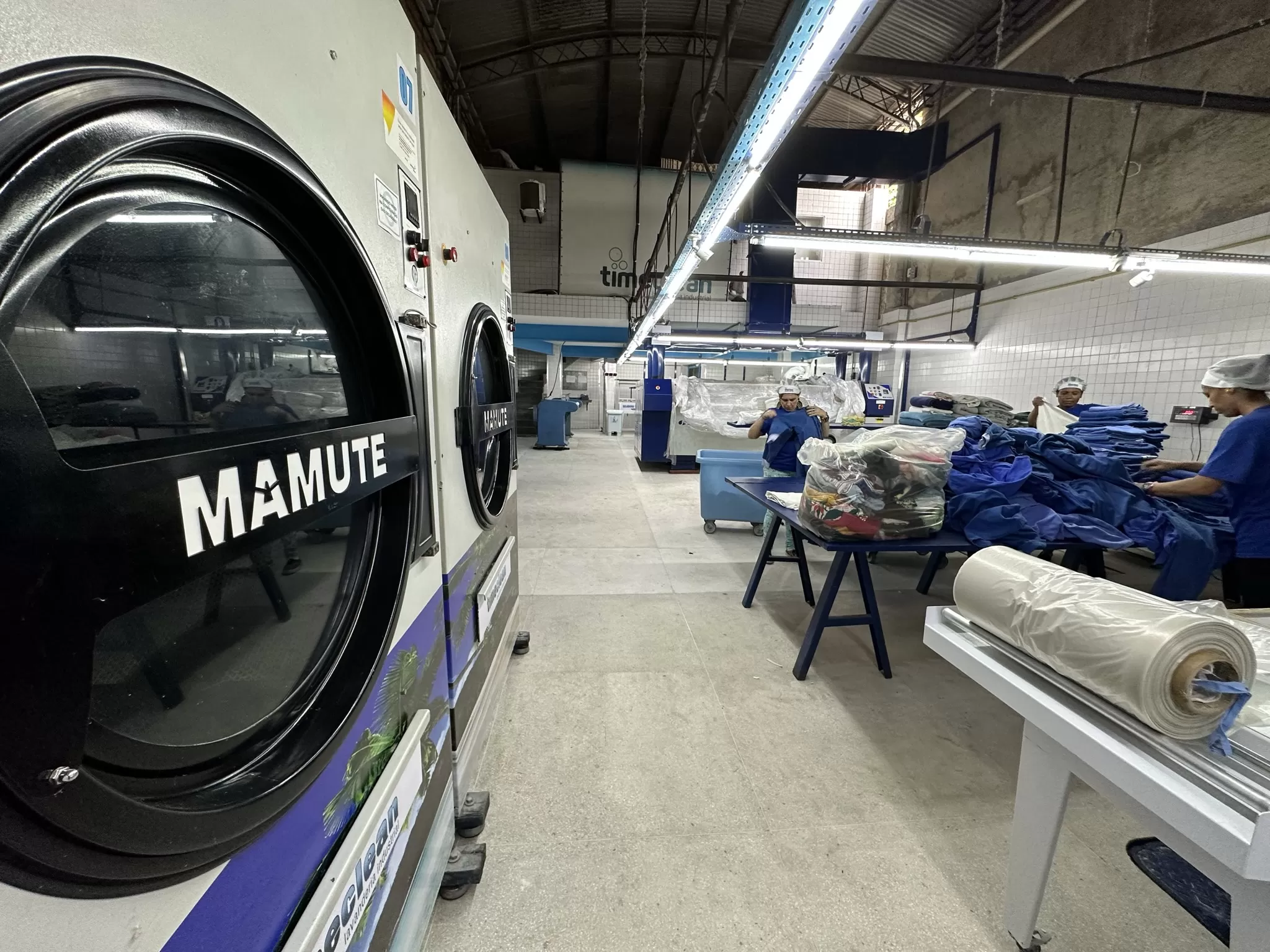 Secadoras industriais Mamute e equipe dobrando enxoval higienizado